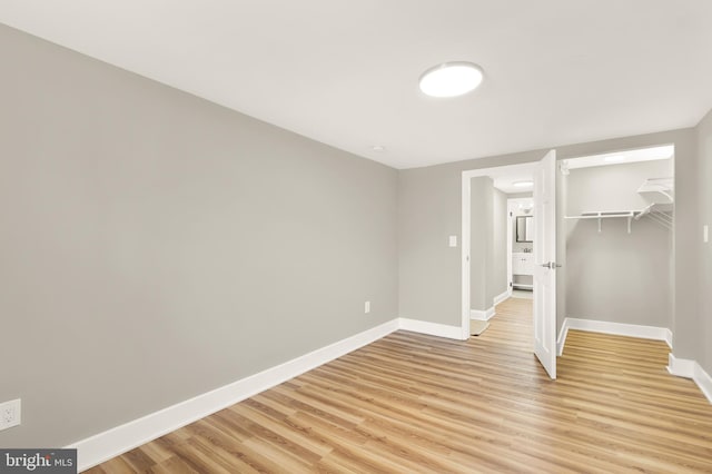 unfurnished bedroom with light wood-style flooring, baseboards, and a closet
