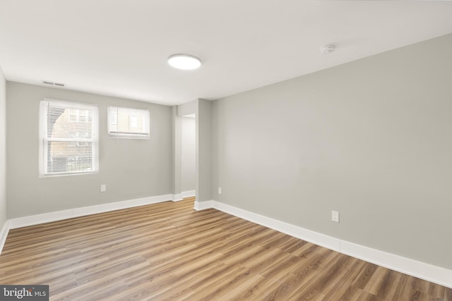 empty room featuring visible vents, baseboards, and light wood finished floors