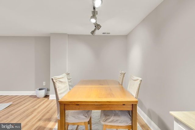 dining room with visible vents, light wood-style flooring, track lighting, and baseboards