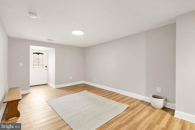 empty room featuring visible vents, light wood-style flooring, and baseboards