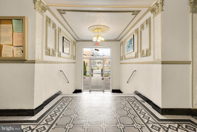 hall with crown molding, baseboards, and a chandelier