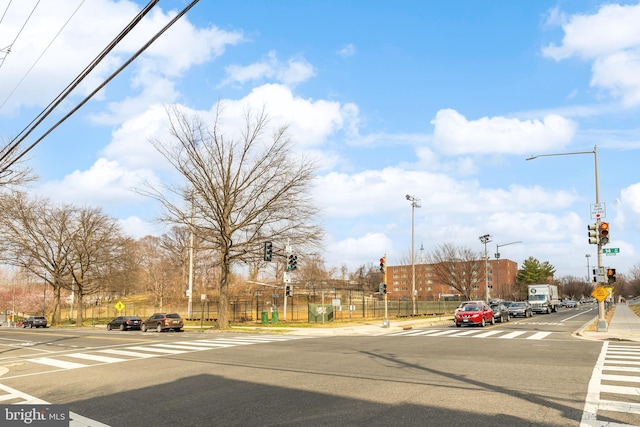 view of road featuring curbs, traffic signs, street lights, and sidewalks