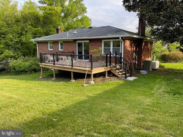 3433 Gregg Rd, Brookeville, MD 20833 - rear view of house featuring a chimney, a deck, brick siding, and a yard