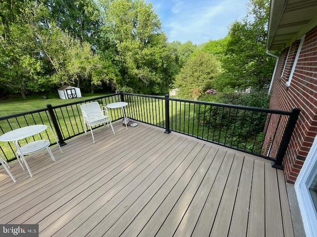 3433 Gregg Rd, Brookeville, MD 20833 - wooden terrace with a storage unit, an outdoor structure, a lawn, and view of wooded area