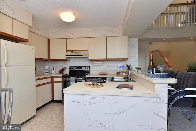 108 120th St Unit 5462, Ocean City, MD 21842 - kitchen with stainless steel range with electric stovetop, under cabinet range hood, cream cabinetry, freestanding refrigerator, and a peninsula
