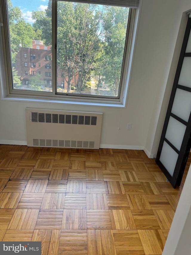 unfurnished room featuring baseboards and radiator heating unit