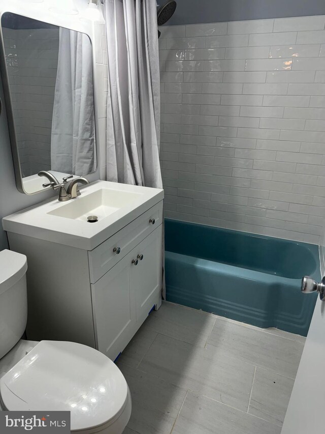 bathroom with toilet, shower / bath combo with shower curtain, and vanity