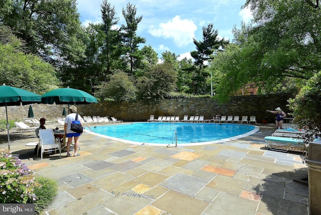 community pool with a patio and fence