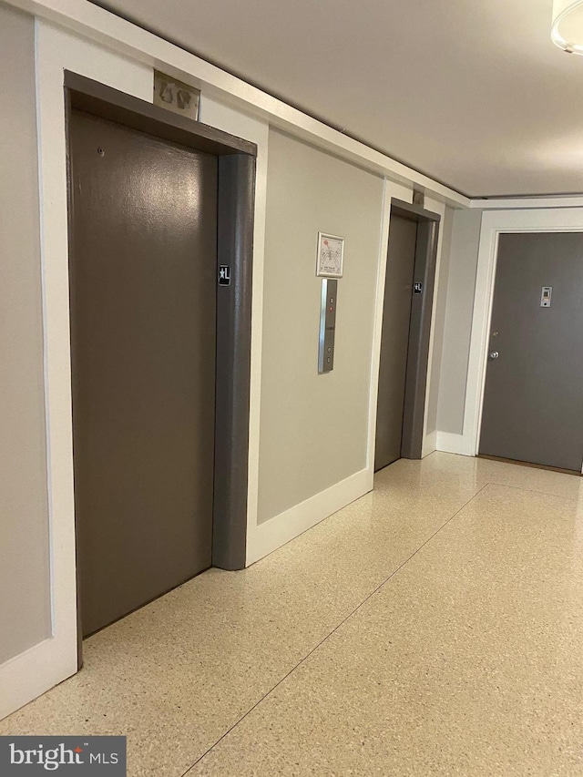 hall with elevator and baseboards