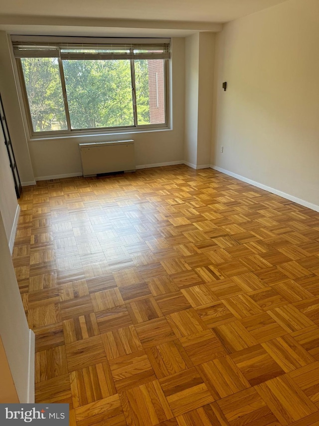 empty room featuring radiator and baseboards