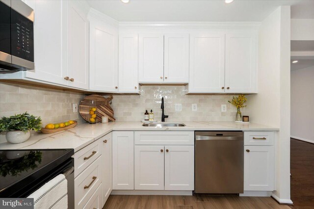 kitchen with white cabinetry, light wood-style flooring, a sink, and stainless steel appliances