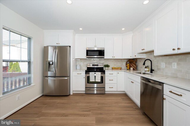 kitchen featuring white cabinets, a sink, appliances with stainless steel finishes, and light wood finished floors