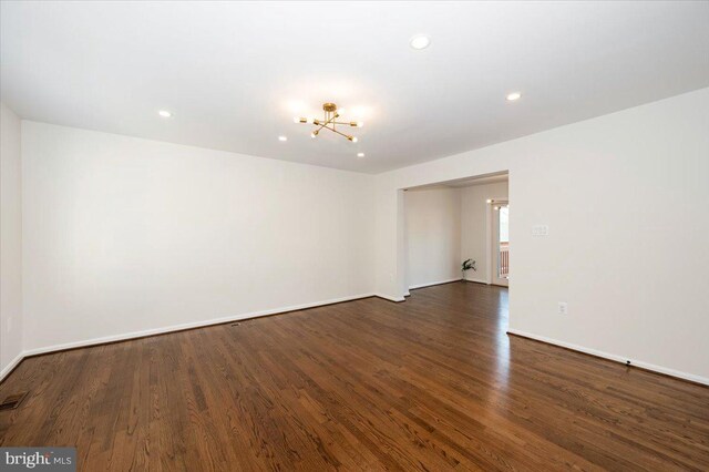empty room featuring baseboards, a notable chandelier, wood finished floors, and recessed lighting