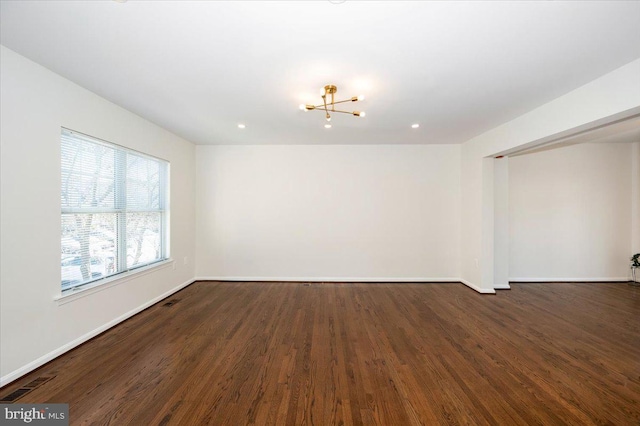 empty room with dark wood finished floors, baseboards, and a chandelier