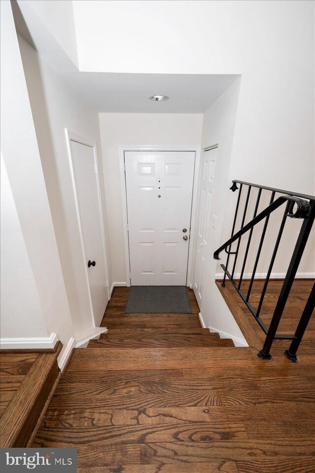 entryway featuring dark wood finished floors, stairs, and baseboards