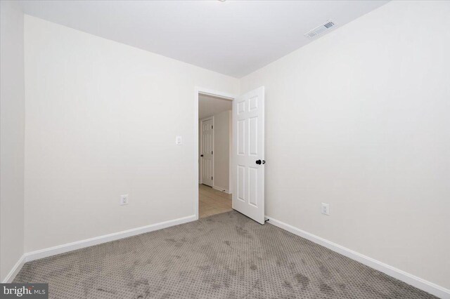 empty room with carpet, baseboards, and visible vents
