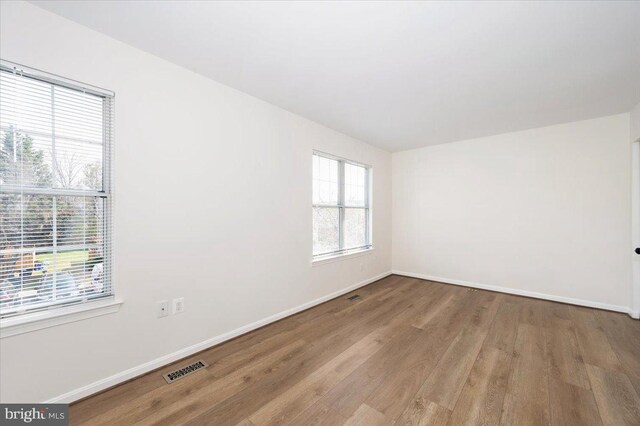 empty room featuring baseboards, visible vents, and wood finished floors