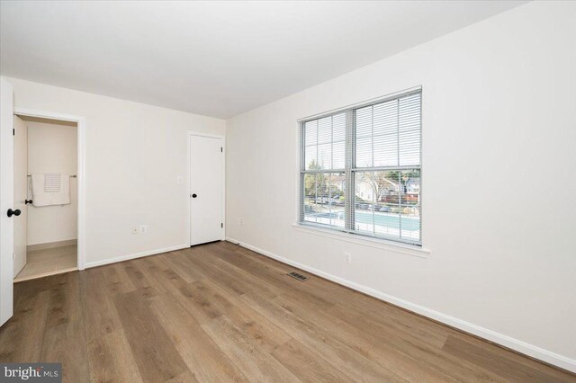 unfurnished bedroom featuring baseboards, visible vents, and wood finished floors