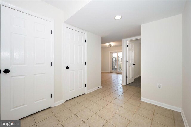 hallway featuring baseboards, recessed lighting, and light tile patterned floors