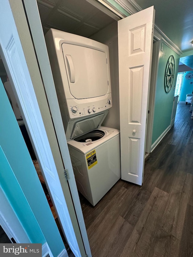 laundry room featuring baseboards, stacked washer and clothes dryer, laundry area, and dark wood-type flooring