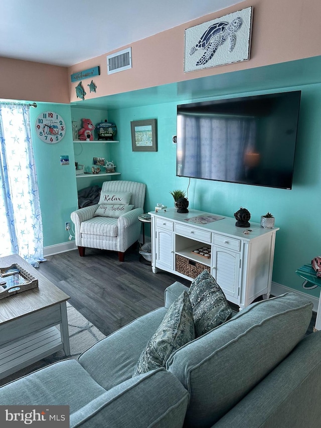 living room with baseboards, visible vents, and wood finished floors