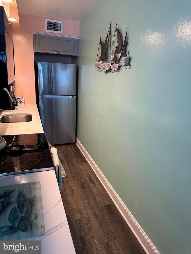 kitchen with visible vents, baseboards, dark wood-type flooring, a sink, and freestanding refrigerator