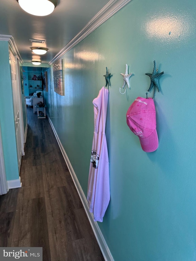 corridor with baseboards, wood finished floors, and ornamental molding