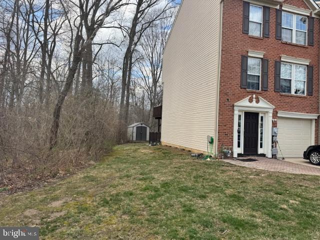 view of home's exterior featuring an outbuilding, a yard, a storage unit, brick siding, and an attached garage