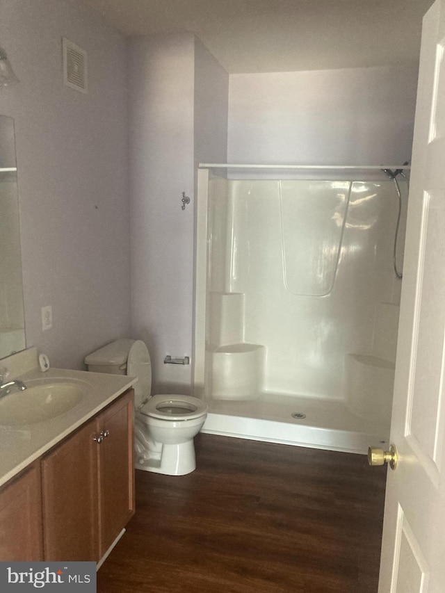 full bathroom featuring vanity, walk in shower, toilet, and wood finished floors