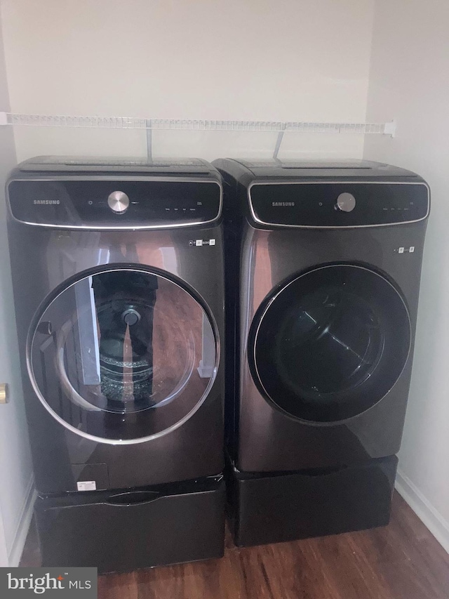 laundry area featuring separate washer and dryer, baseboards, and wood finished floors