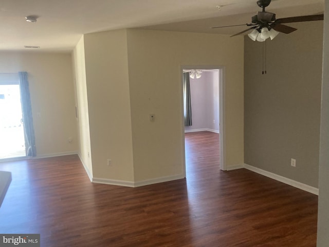 empty room with dark wood finished floors, visible vents, baseboards, and ceiling fan