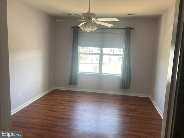 unfurnished room with dark wood-type flooring, visible vents, ceiling fan, and baseboards