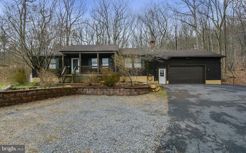 view of front of house with covered porch, a garage, and aphalt driveway