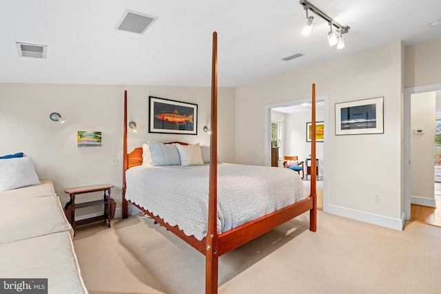 bedroom with track lighting, light colored carpet, baseboards, and visible vents