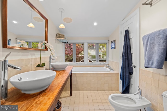 full bathroom with tile patterned flooring, a bath, tile walls, and a sink
