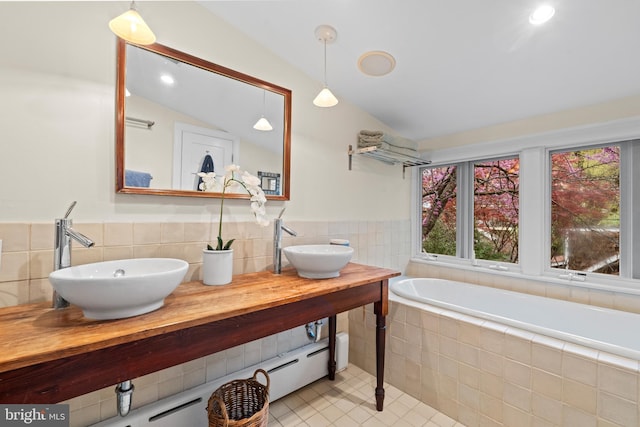bathroom with a sink, tile walls, tile patterned floors, and lofted ceiling
