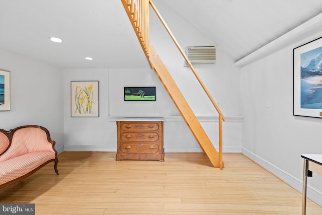 sitting room with baseboards, a wall mounted air conditioner, light wood-type flooring, recessed lighting, and stairs
