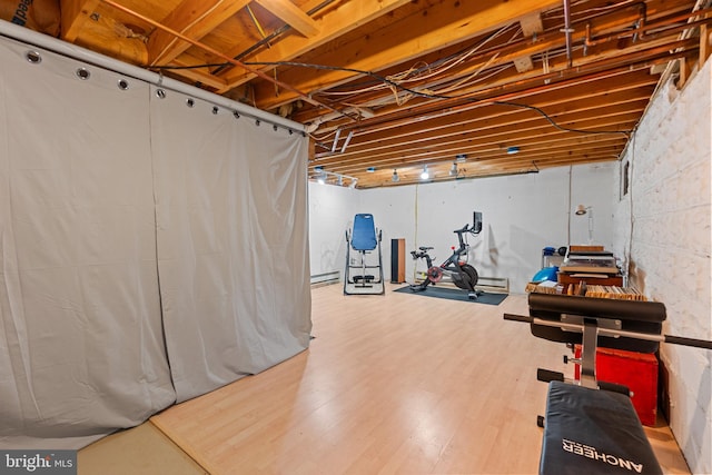 unfinished below grade area featuring wood finished floors and a baseboard heating unit