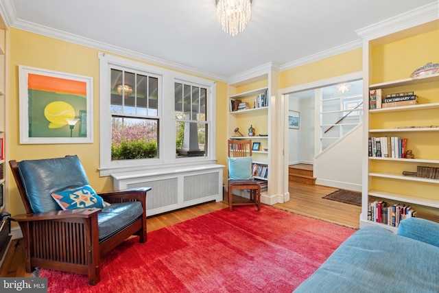 sitting room with radiator heating unit, crown molding, a chandelier, and wood finished floors