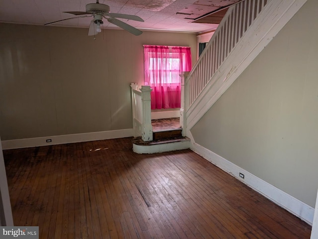 spare room with ceiling fan, baseboards, hardwood / wood-style floors, and stairs