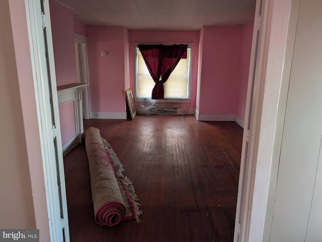 hall with baseboards and wood-type flooring