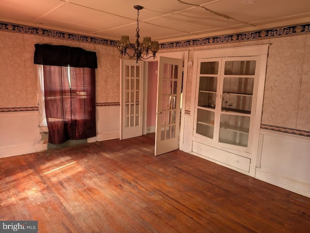 spare room featuring a chandelier, french doors, and hardwood / wood-style floors