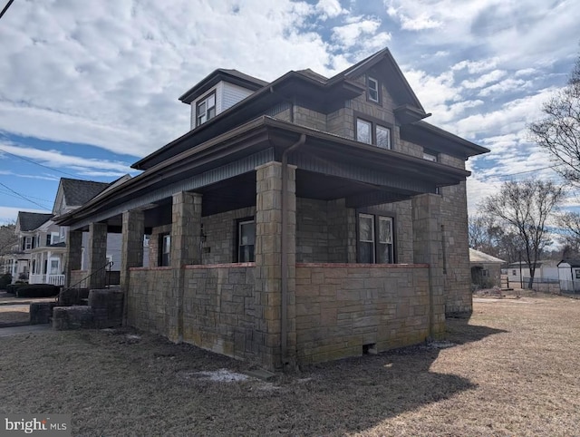 view of side of home featuring a porch and stone siding