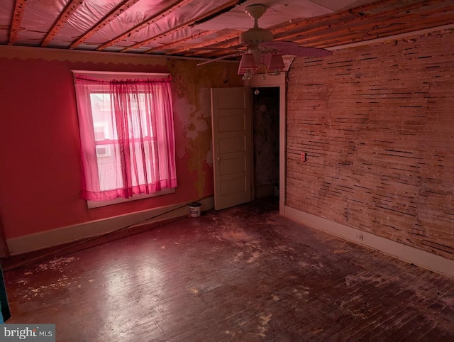 spare room featuring wood finished floors, a ceiling fan, and baseboards