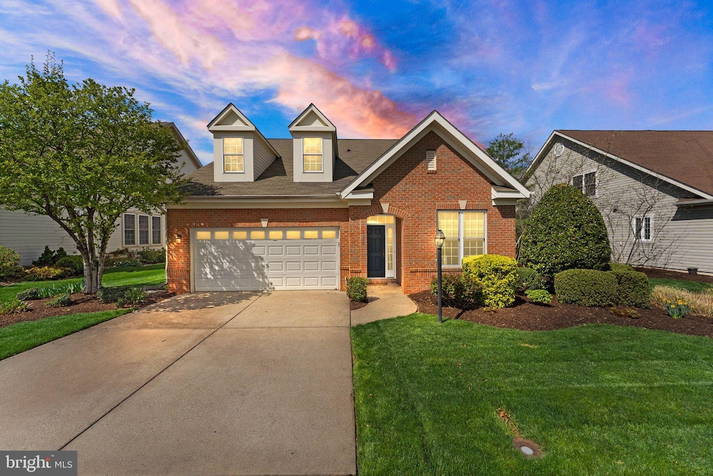 view of front facade featuring brick siding, an attached garage, a yard, and driveway