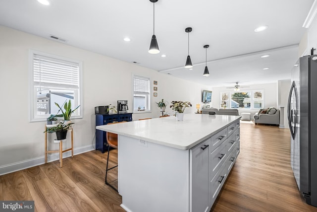 kitchen featuring dark wood-style flooring, open floor plan, freestanding refrigerator, a kitchen breakfast bar, and a kitchen island