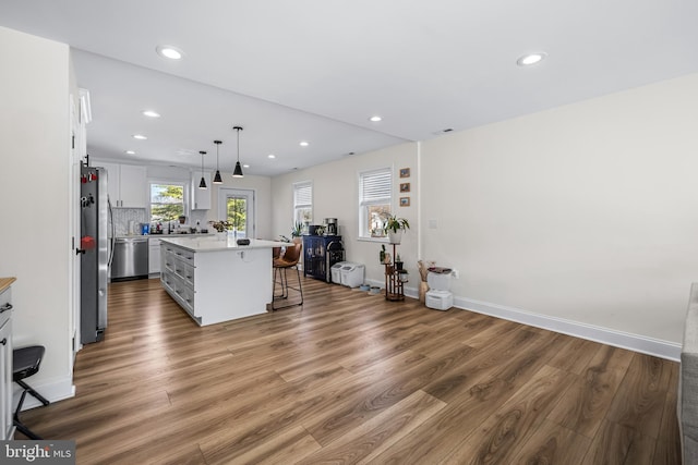 kitchen featuring a breakfast bar, light countertops, white cabinets, appliances with stainless steel finishes, and wood finished floors