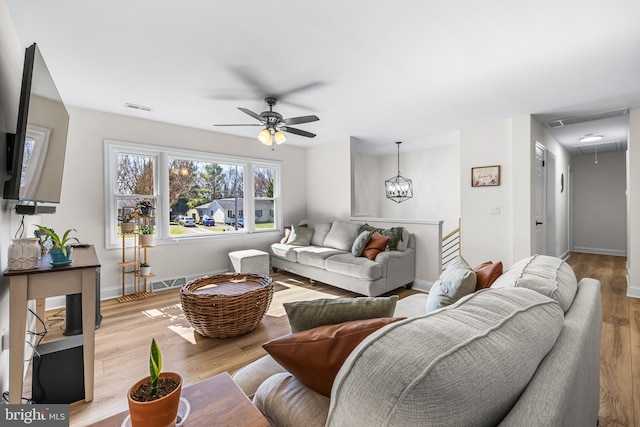 living room with ceiling fan, visible vents, wood finished floors, attic access, and baseboards