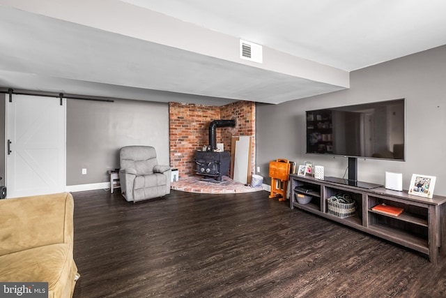 living area featuring visible vents, a wood stove, a barn door, and wood finished floors