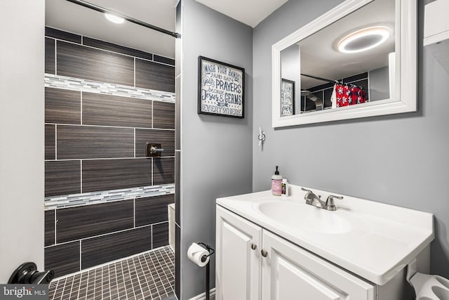 full bathroom with a tile shower and vanity